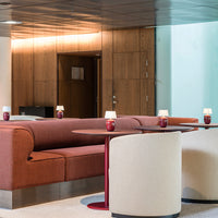 Rust-colored sofa with modern cream seating, sleek tables, and soft lighting in a stylish interior setting.