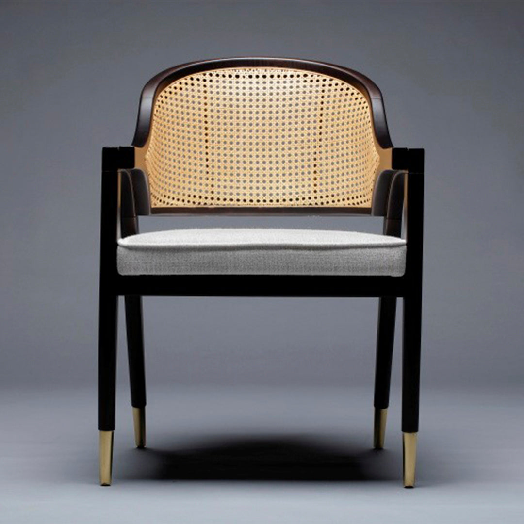 Modern black wooden chair with a caned backrest and grey cushion, featuring gold-tipped legs for a stylish contrast.