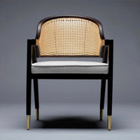 Modern black wooden chair with a caned backrest and grey cushion, featuring gold-tipped legs for a stylish contrast.
