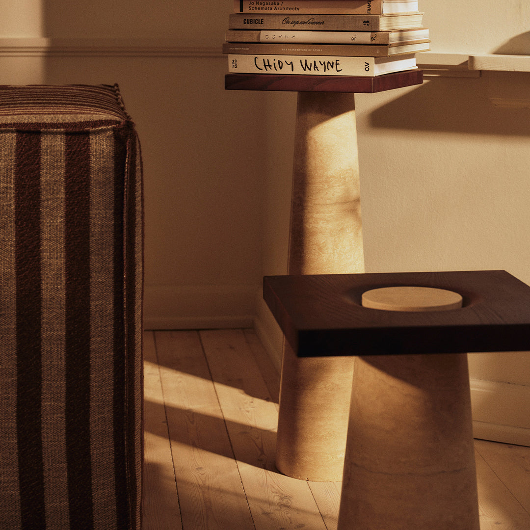 "Modern room with a striped brown cushion and light-toned sculptural table featuring a dark square top."
