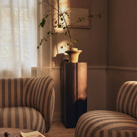 Striped beige and cream upholstery on cozy armchairs contrasts with a sleek, dark wooden pedestal.