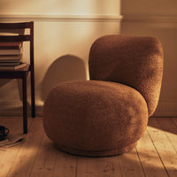 Textured brown chair with a rounded, sculptural design, set against warm wooden flooring and soft lighting.