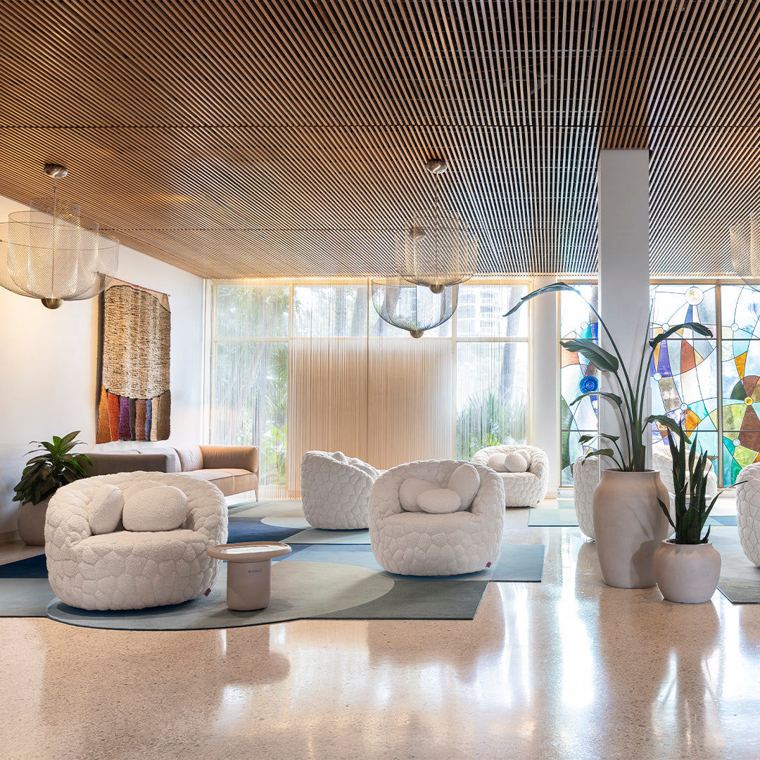 Cozy white round chairs on soft blue rugs with earthy tones and vibrant stained glass accents. Bright and inviting space.