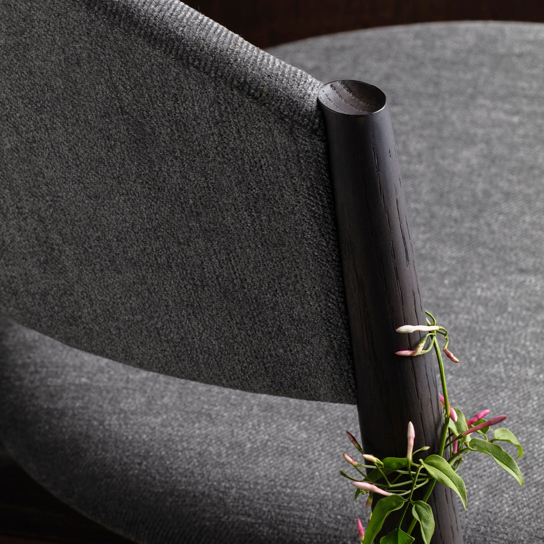 Gray upholstered chair with a sleek black armrest and subtle textured fabric, perfect for modern decor.