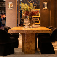 Natural wood table with a textured surface, complemented by deep black velvet chairs and neutral-toned decor.