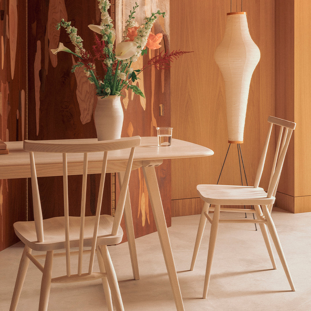 Light wood chairs and table with soft neutral tones, complemented by floral arrangement and textured patterns in background.