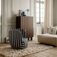 "Black and white striped accent chair in a stylish room with wood tones and neutral textures."