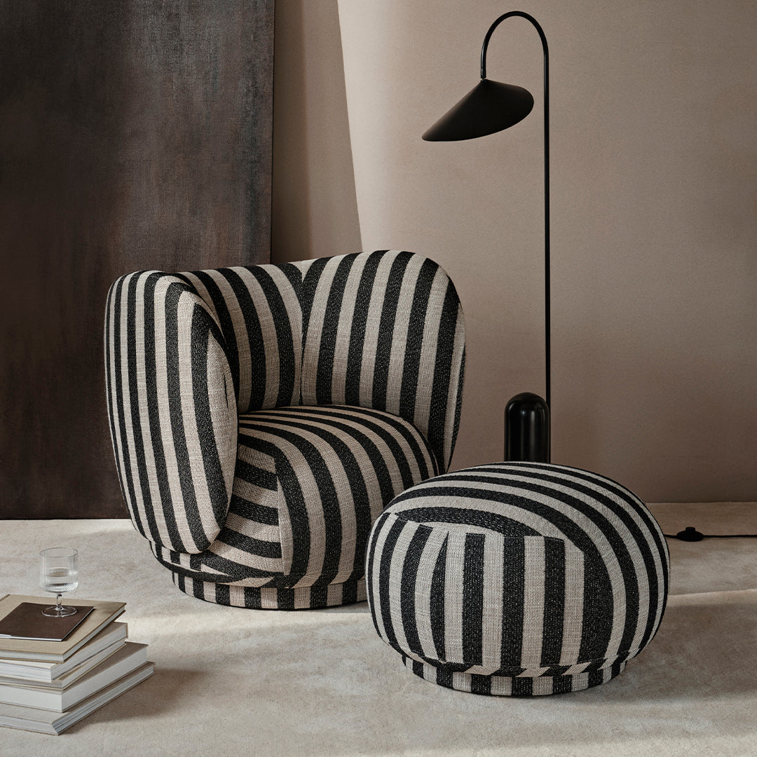 Black and cream striped armchair and ottoman set, featuring bold patterns for a modern aesthetic.
