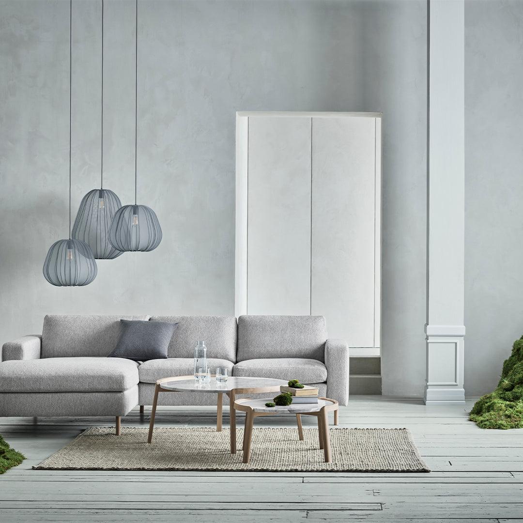 Gray sofa with subtle textures, clear glass pendant lights, white cabinet, and neutral-colored rug on a light floor.