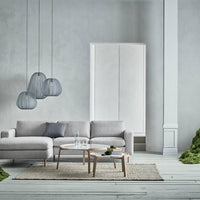 Gray sofa with subtle textures, clear glass pendant lights, white cabinet, and neutral-colored rug on a light floor.