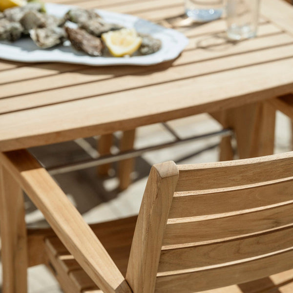 Natural wood dining table with slatted design and matching chair, featuring warm tones of light brown and honey beige.