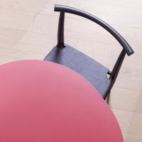 Round pink table with a gray upholstered chair showcasing a subtle dotted pattern and smooth finishes.