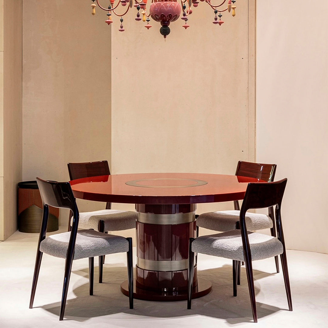 Round red dining table with a glossy finish, surrounded by four dark wooden chairs with light gray upholstery.
