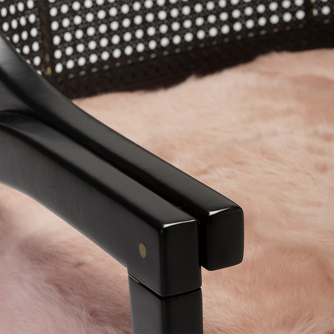 Black chair armrests atop soft pink fur, with a textured woven back detail. Modern and stylish design elements.