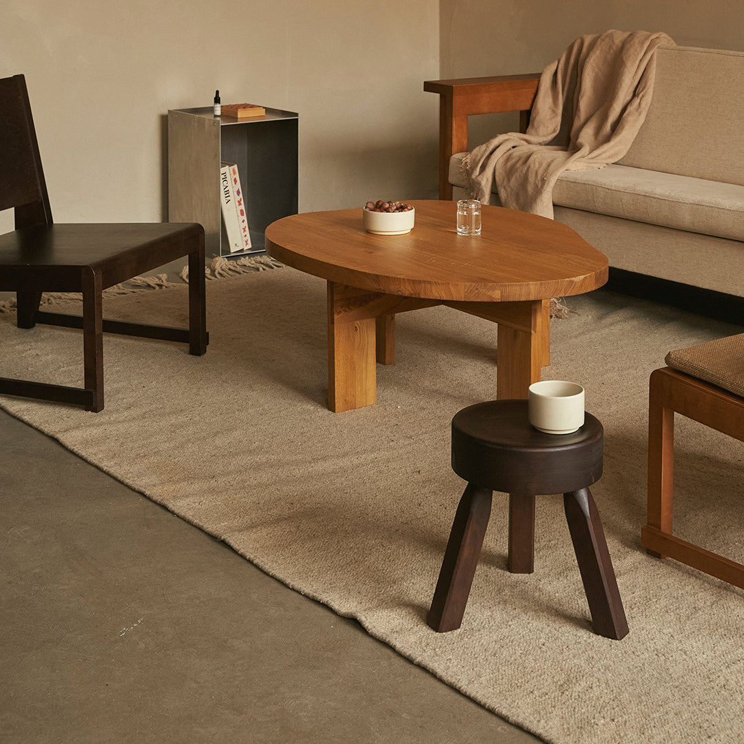 Natural wood tones with a beige sofa, dark brown chairs, and a textured neutral rug create a cozy, modern living space.