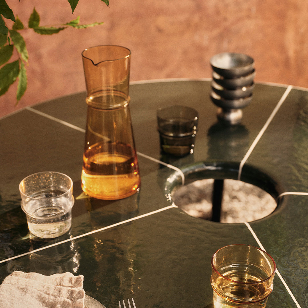 Green marble table with clear, amber, and black drinkware; natural textures and elegant patterns create a stylish setting.