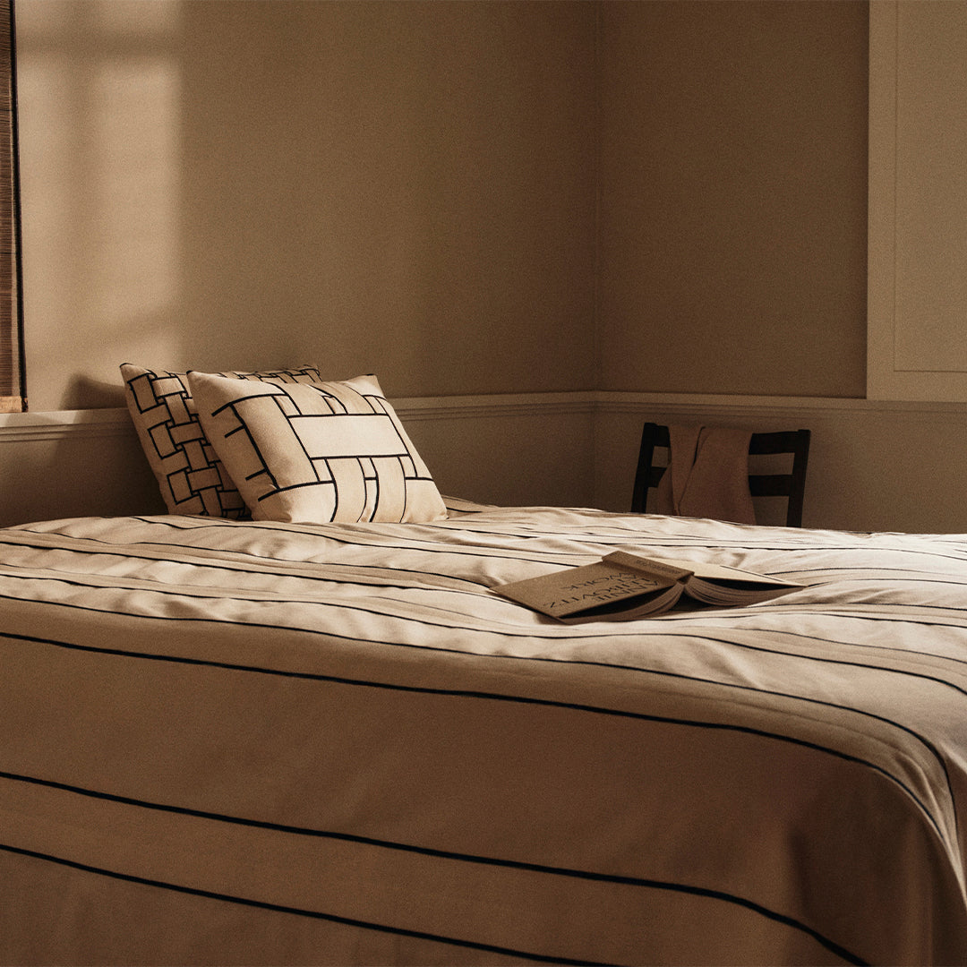 Neutral beige bedding with black linear patterns and matching pillow covers, creating a modern, minimalist aesthetic.