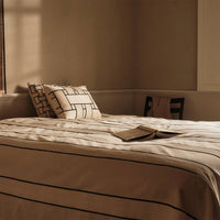 Neutral beige bedding with black linear patterns and matching pillow covers, creating a modern, minimalist aesthetic.