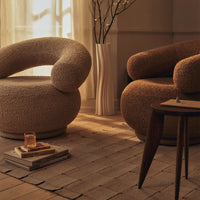 Two plush, curved armchairs in warm beige and soft brown with textured fabrics, set in a cozy, minimalist atmosphere.