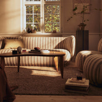 Striped beige and cream sofa with natural lighting, surrounded by earthy tones and textures in a cozy living room setting.