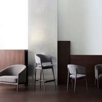 Gray upholstered chairs with sleek lines against warm wooden accents and a reflective silver backdrop.