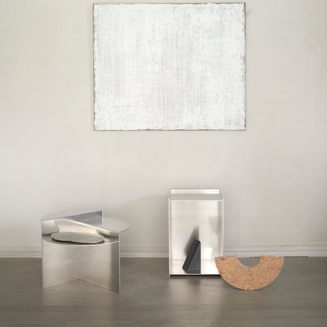 Silver metallic furniture with sleek, modern shapes, complemented by a neutral beige and white accent wall.