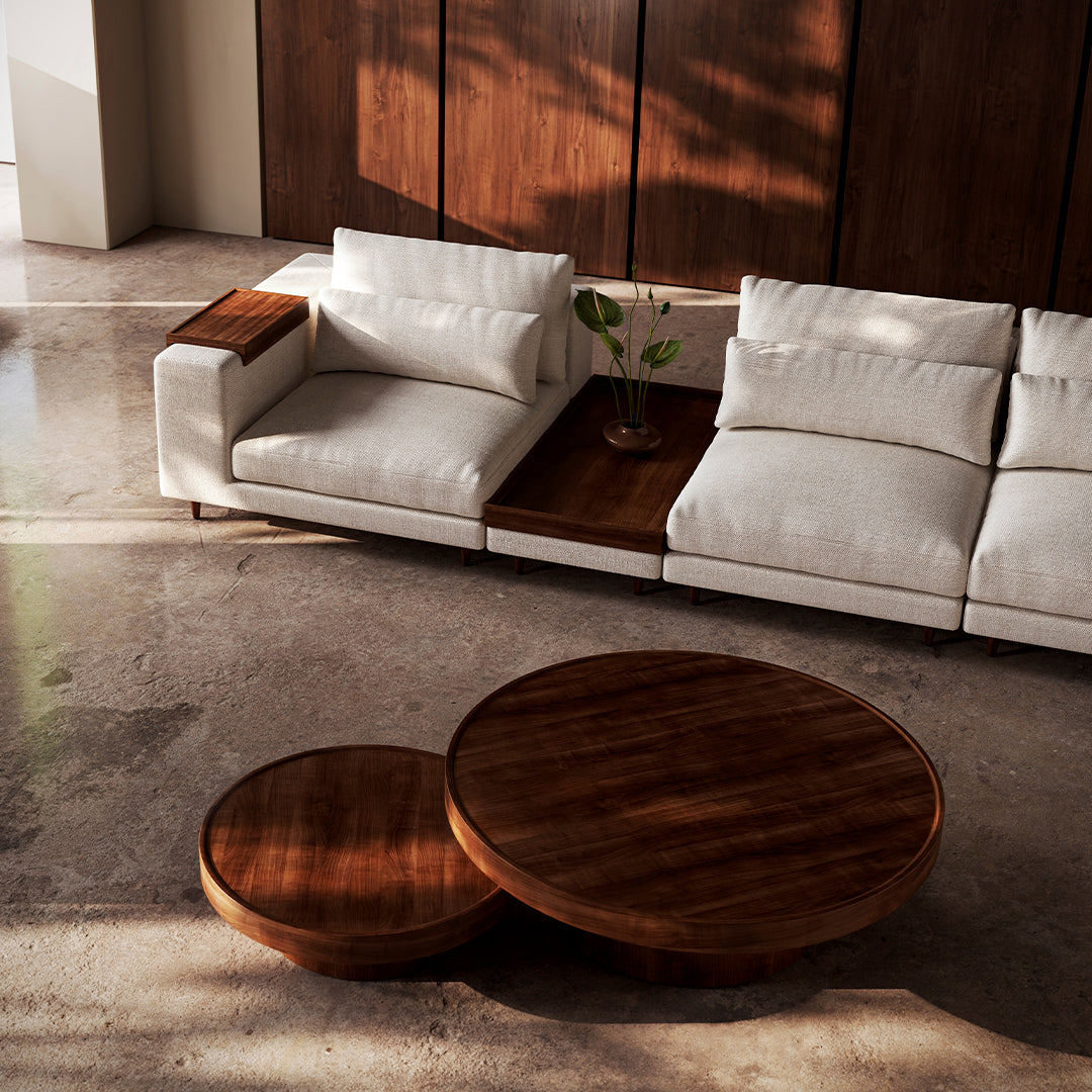 "Modern white sofa with plush cushions and dark wood round coffee tables in a stylish, minimalistic interior."