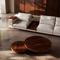 Elegant white sofa with wood accents, paired with round wooden coffee tables in a modern, minimalist setting.