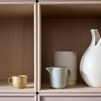 Decorative kitchenware in gold, mint green, beige, and white, displayed on natural wood shelves. Stylish and modern design.