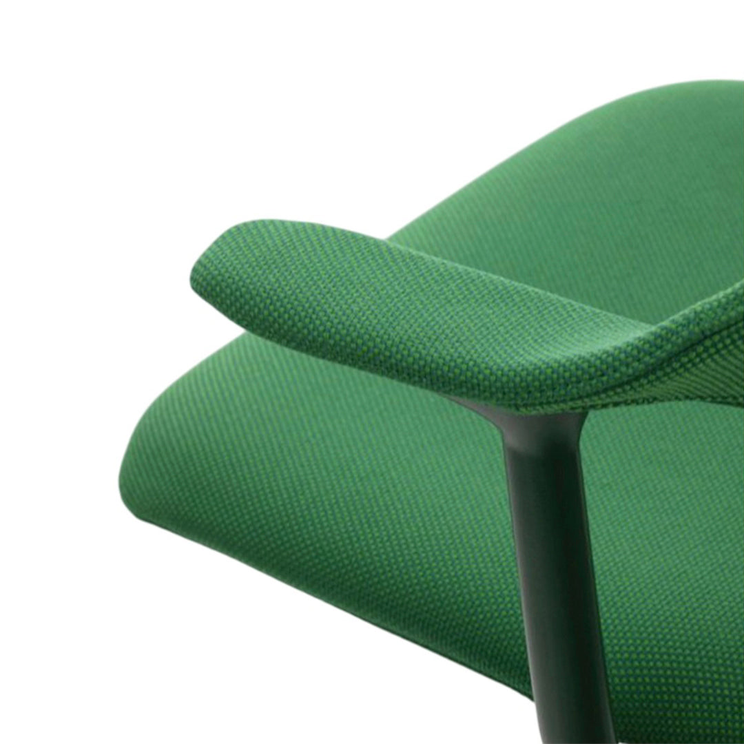 Close-up of green patterned fabric on chair armrest and seat, showcasing vibrant shades and textured weave.