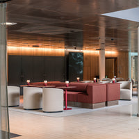 Modern lounge with red and beige seating, sleek wood accents, and a polished metallic ceiling.