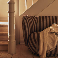 Brown striped sofa with deep textures, complemented by a soft beige throw blanket in a warm, inviting setting.