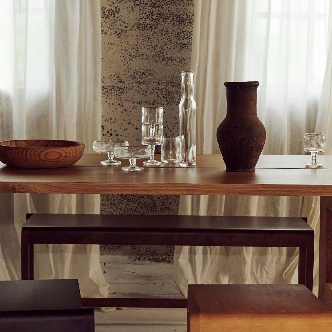 Stylish wooden tabletop with natural tones, elegant glassware, and earthy ceramic accents against a soft, textured backdrop.