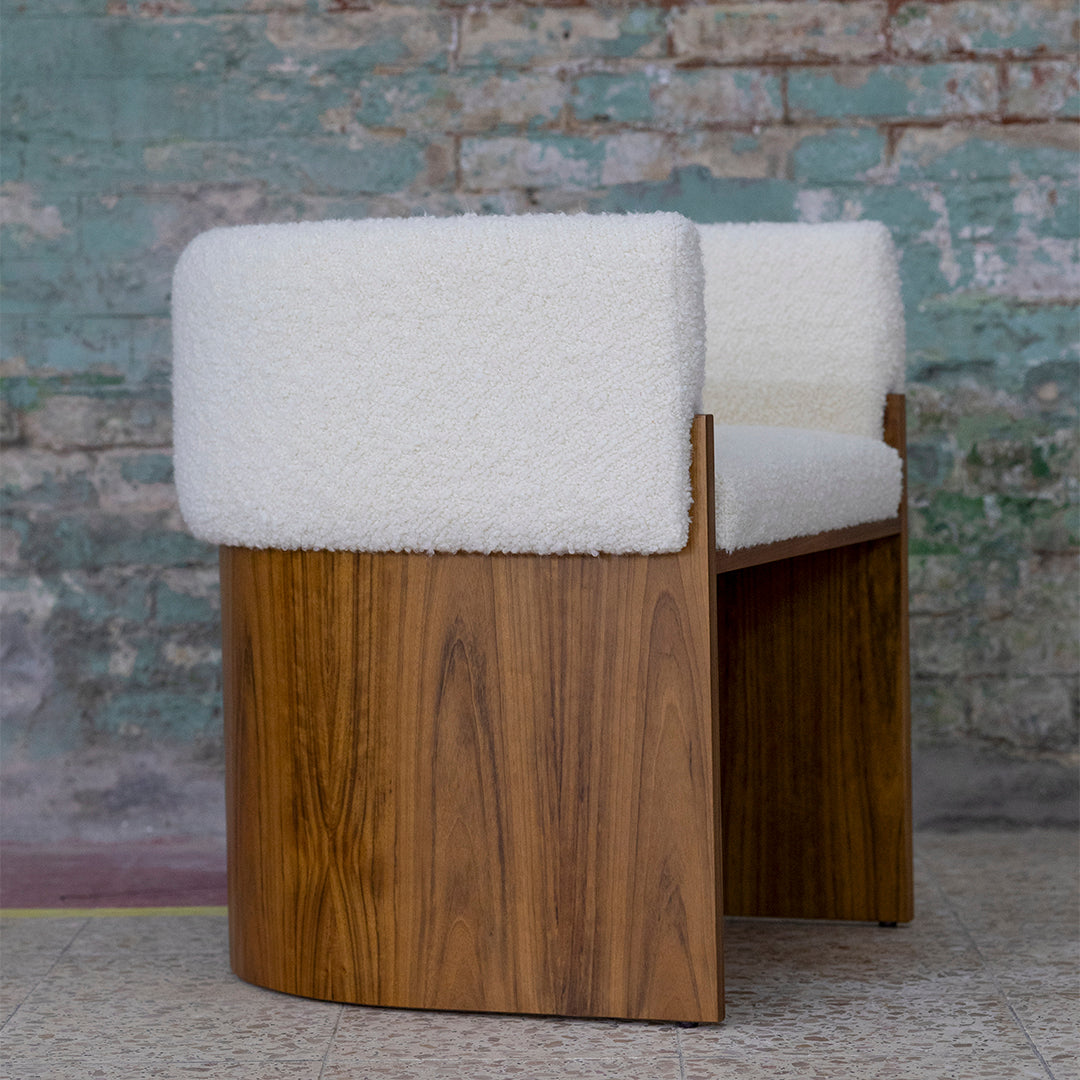 White boucle upholstery with a warm wood base, featuring a smooth, curved design and textured contrast.