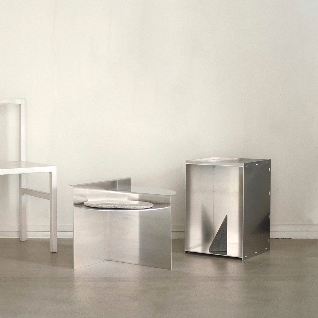 Modern metallic side tables with sleek silver finishes and geometric shapes, set against a minimalist background.