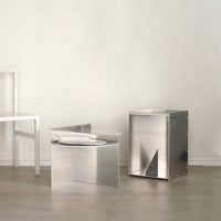 Modern metallic side tables with sleek silver finishes and geometric shapes, set against a minimalist background.