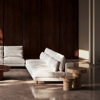 Modern white sofa with clean lines, paired with natural wood accent tables, against a dark wood backdrop.