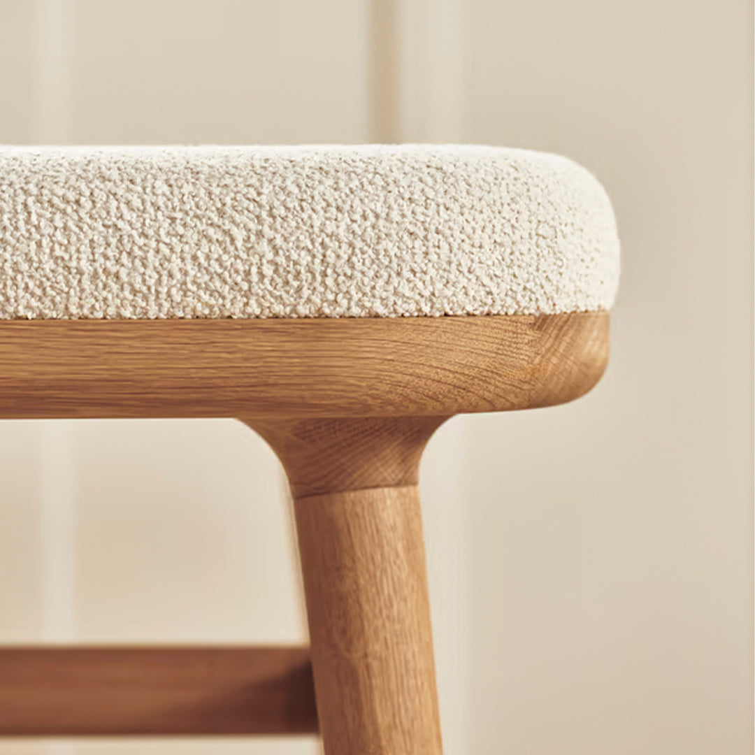 Cream textured upholstery on a wooden stool, featuring natural beige tones and soft, tactile patterns.