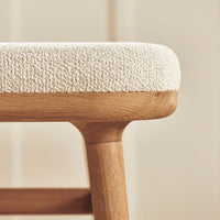 Cream textured upholstery on a wooden stool, featuring natural beige tones and soft, tactile patterns.