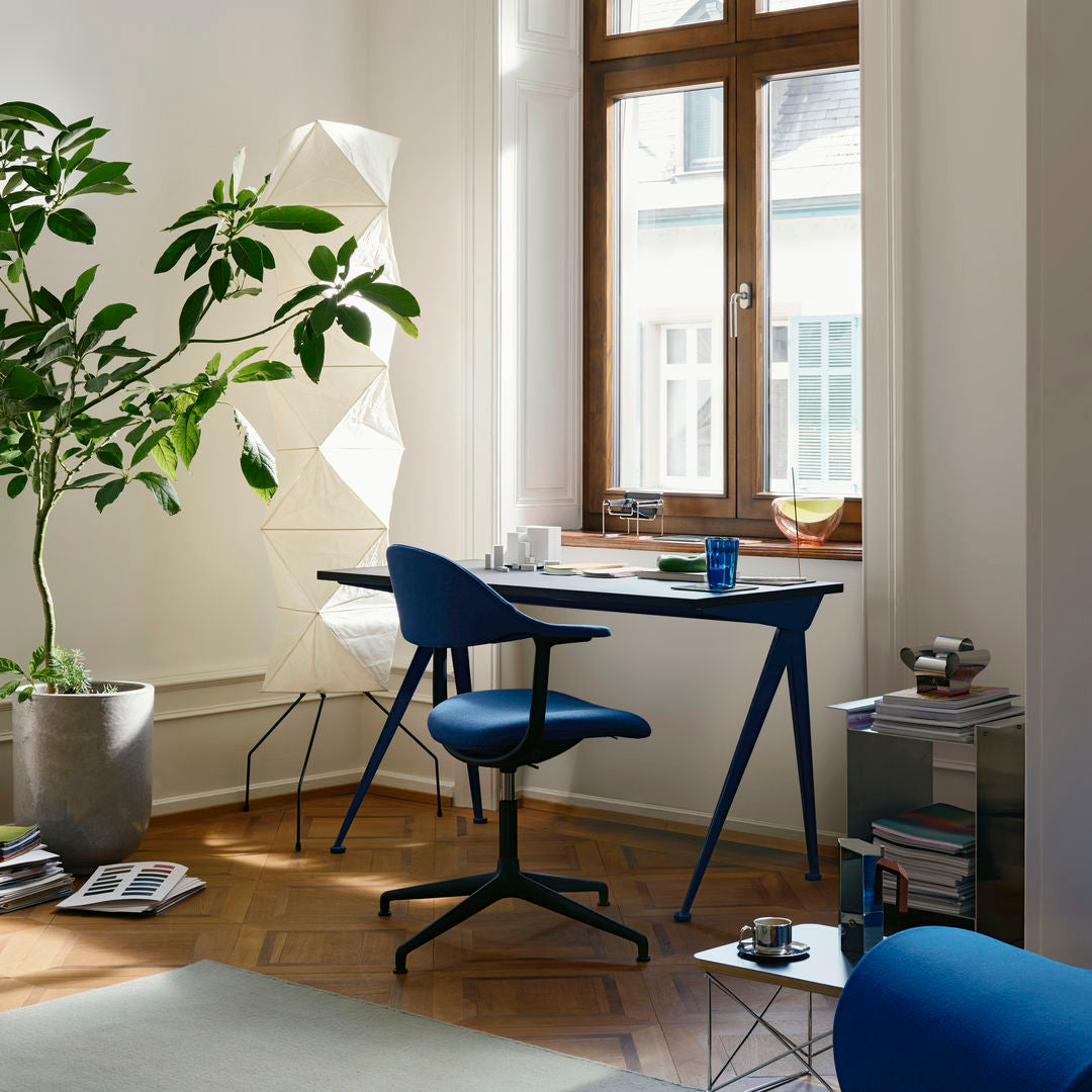 Blue chair and desk with geometric shapes, warm wooden accents, and a neutral rug in a bright, modern workspace.