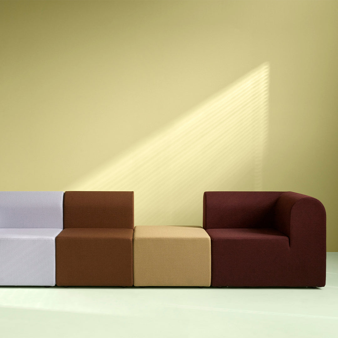 Colorful modular sofa with lavender, brown, tan, and burgundy upholstered sections against a soft yellow background.
