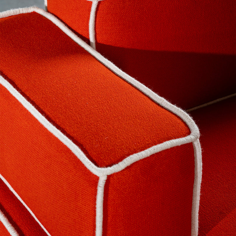 Bright orange upholstery with contrasting white piping, showcasing a modern, bold design. Perfect for vibrant decor.