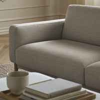 Light gray upholstered sofa with a smooth, textured pattern, paired with neutral-toned decor elements.