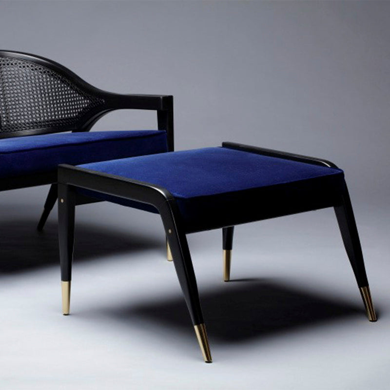 Navy blue velvet ottoman with a sleek black frame and gold accent legs, perfect for modern decor.