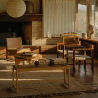 Warm wood tones, beige textiles, and soft shadows create a cozy, inviting living room ambiance. Minimalist patterns featured.
