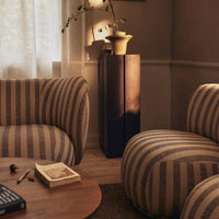 Brown and cream striped lounge chairs with a wooden table in a cozy, sunlit living room setting.
