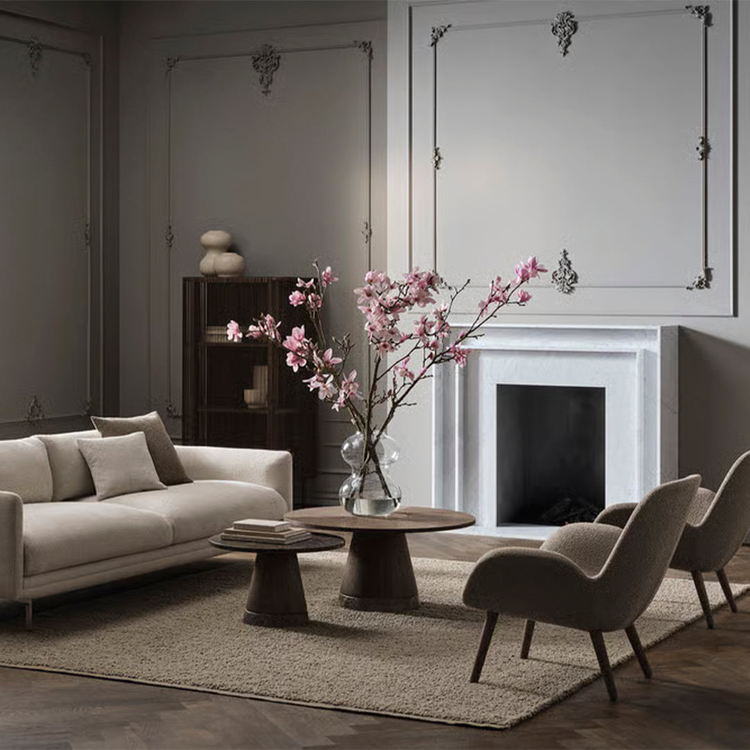 Stylish beige sofa with soft pink florals, neutral accents, and textured rugs in a modern living room setting.
