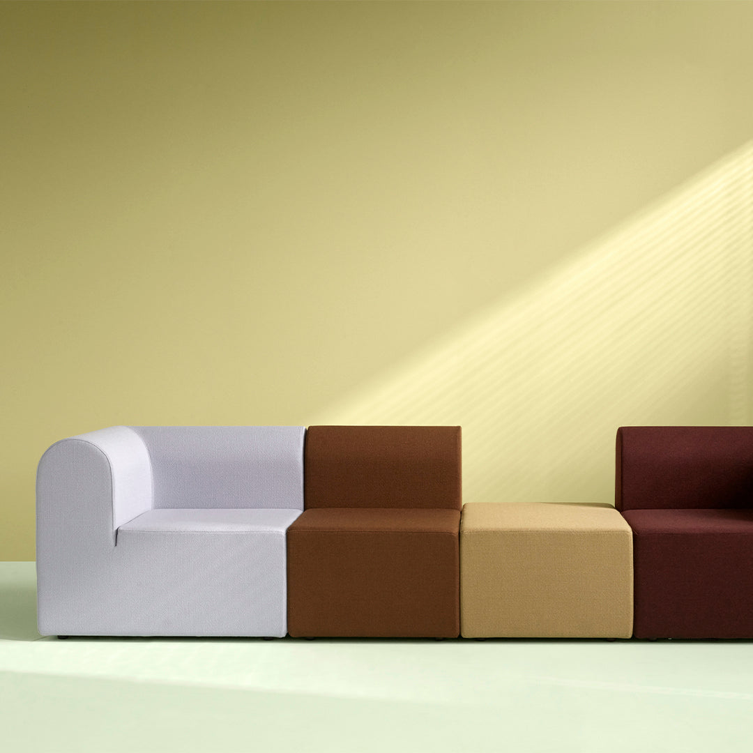 Modern sofa with white, brown, and beige blocks on a soft green floor and yellow wall background. Versatile color scheme.