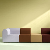 Modern sofa with white, brown, and beige blocks on a soft green floor and yellow wall background. Versatile color scheme.