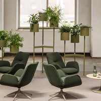 Green upholstered chairs with olive planters and lush greenery against a neutral backdrop. Modern, stylish, and natural.